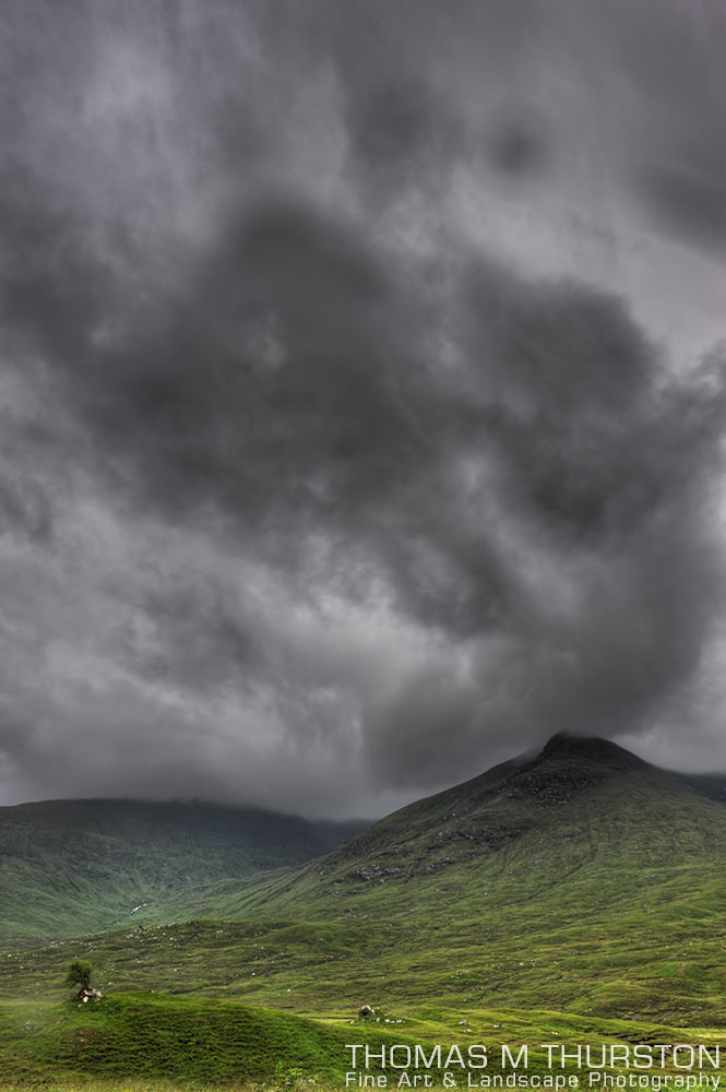 Green shades of Scottish hills juxtapose an ominous sky just before a storm.
